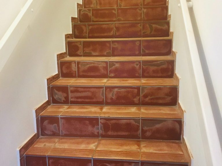 Geflieste Treppe mit weißen Geländern an den Seiten.