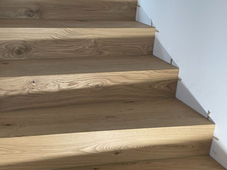 Parketttreppe mit hellen Stufen und Schatten, die von natürlichem Licht erzeugt werden.