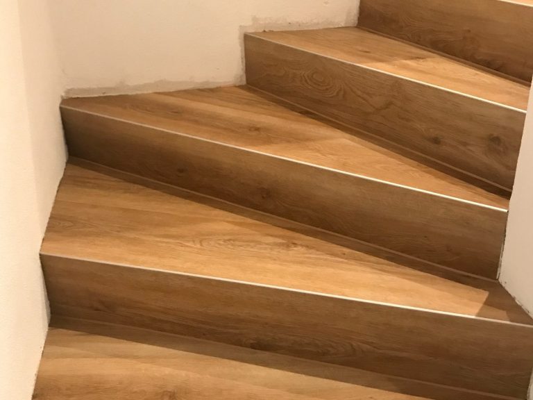 Treppe mit hellbraunen Vinyl-Treppenstufen und grauem Wandanstrich.