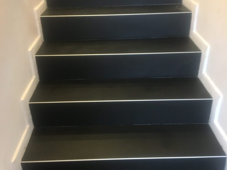 Schwarze Treppe mit weißen Kanten, die nach oben führt.